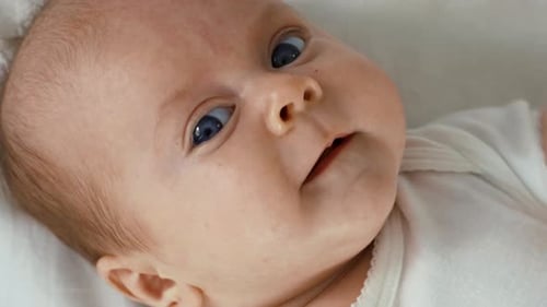 Newborn Baby Two Months Old Lies On White Bed Sheet