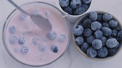 Mixing Blueberries into Delicious Pink Yogurt