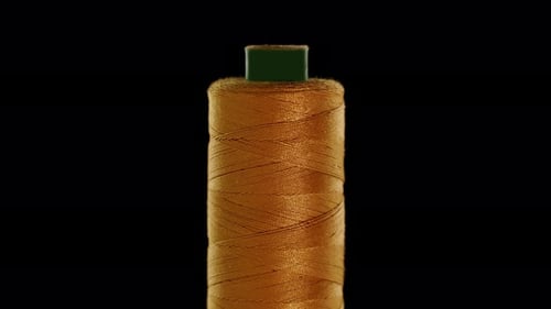 Gold Colored Sewing Thread on a Black Background