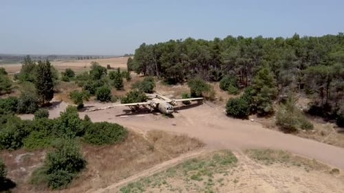 aerial slow forward, zoom in drone shot of an old dismantled army plane monument placed on an empty