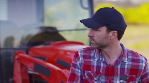 Man Poses with Red Tractor in Rural Setting