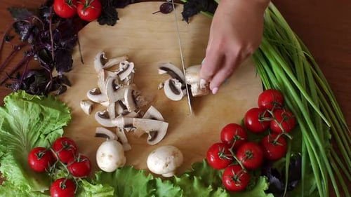 Woman Slicing Mushrooms with Fresh Vegetables