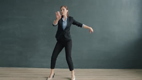 Portrait of Joyful Young Businesswoman Dancing in Studio on Black Background