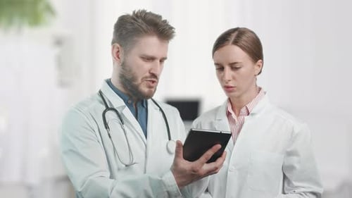 A Doctors are Talking and Checking Results on Digital Tablet in a Hospital