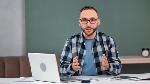 Man Talking at Desk with Laptop and Tablet