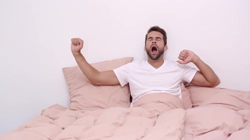Man Wakes Up and Stretches in Bed