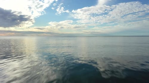 LUFTAUFNAHME: Sehr tief über der Meeresoberfläche in den Horizont fliegen mit blauem bewölktem Himmel