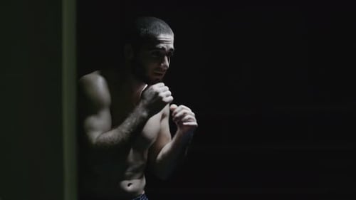 Fighter Boxing Alone in Dark Gym