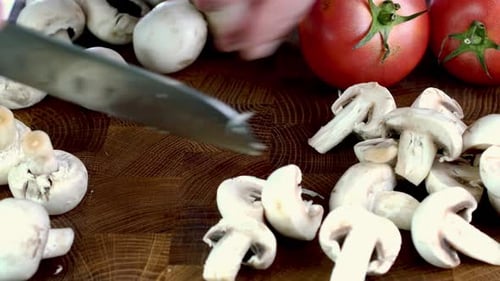 Schneiden von rohen Champignons Pilze auf Holzschneidebrett mit Messer in der heimischen Küche