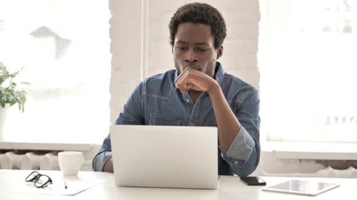Hombre africano pensativo trabajando en portátil