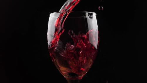 Vinho Vinho tinto derramando em copo de vinho sobre fundo escuro. Vinho rosé saindo da garrafa. Lento m