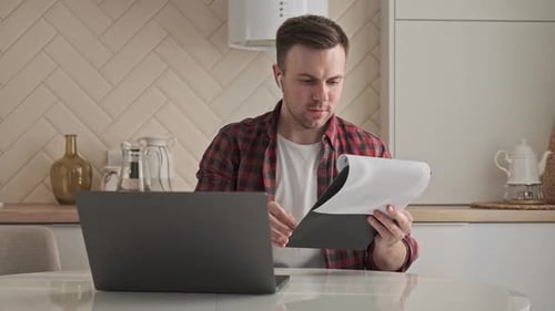 Young Adult Working on Laptop in Kitchen