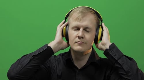 Guy Listens To Music in Wireless Yellow Headphones and Dances, Green Screen