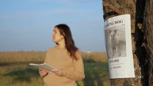 Nervous Lady with Flyers in Park Focus on Missing Dog Poster