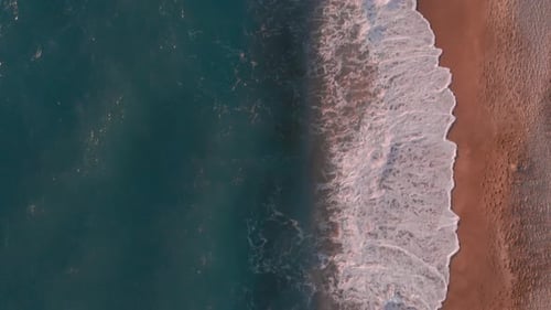 Giant sea waves crashing on sandy beach at sunset