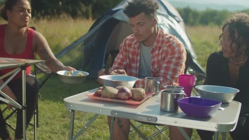Positive Diverse Multiracial Hikers Preparing Camp Meal at Campsite in Mountains on Trek