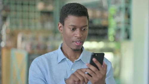 Young Adult Celebrates Success on Smartphone