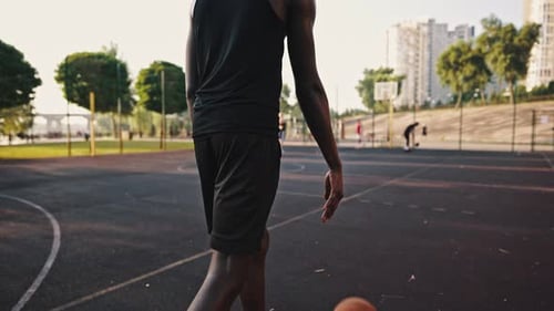 Vue arrière d'un basketteur noir dribblant le ballon sur le terrain