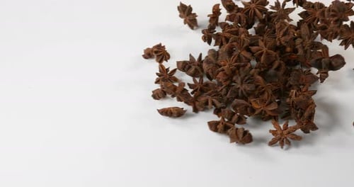 Star Anise Falling Onto a White Surface