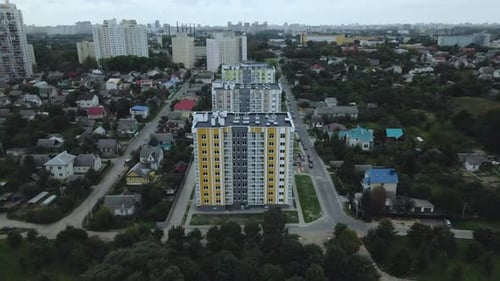 City block. Modern multi-storey buildings among cottages. Flying at dusk at sunset.