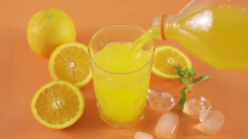 Pouring Refreshing Orange Juice in a Glass with Ice