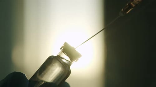 Syringe Drawing Medicine from Vial in Golden Light