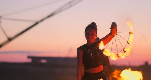 Female Fire Performer Spinning Fiery Wheel at Sunset