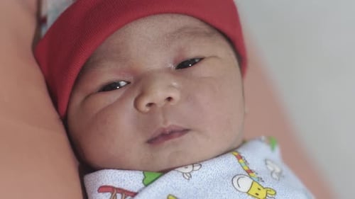 Close-up of Content Newborn Infant in Red Hat