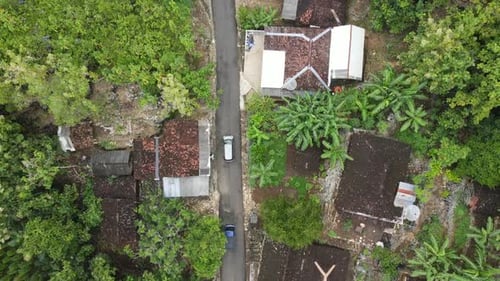Aerial view of a car riding on the small road through village on the countryside in Indonesia