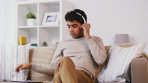 Man Relaxing With Tablet and Headphones At Home