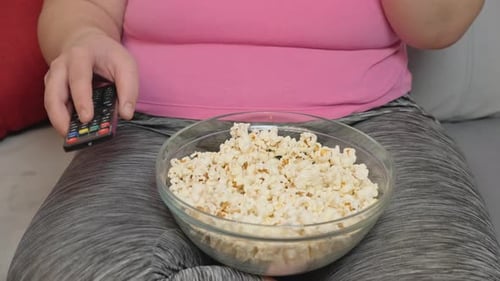 Woman Eating Popcorn and Watching Television at Home
