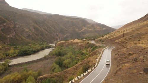 Scenic Mountain Road with River and Car
