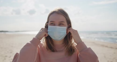 Young Attractive Woman Taking Off Protective Mask Making a Breath at the Beach