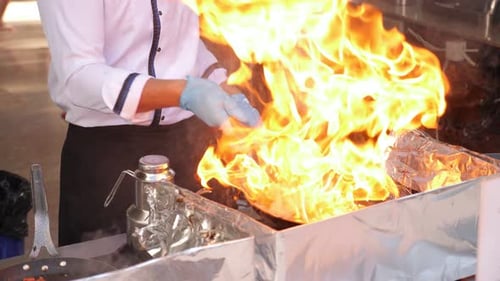A Closeup of a Restaurant Chef Cooking on Fire in an Outdoor Kitchen