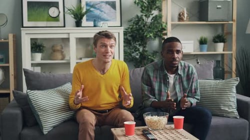 Two Friends Celebrate Together on Couch Indoors