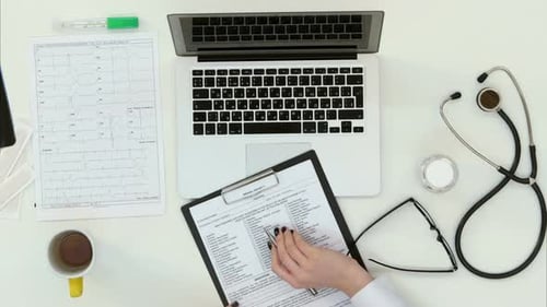 Female Doctor Hands Filling in Medical History Form