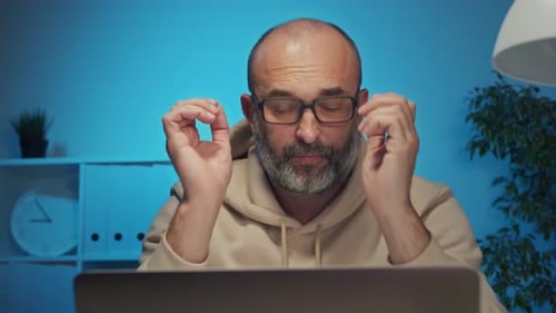 Man Working on Laptop, Appearing Stressed