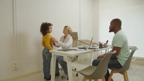 Caring Pretty Female Physician Examining Adorable Multiethnic Little Boy with Stethoscope at Clinic
