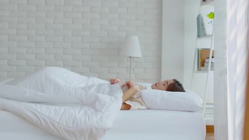 Beautiful Asian young woman close her eyes lying on bed and sleep in cozy bedroom