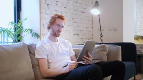Online Video Chat on Tablet by Redhead Man in Office