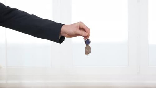 Man Gives Key with House Shaped Breloque to Woman in Room