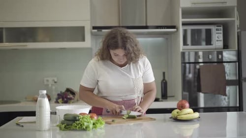 Woman Slicing Vegetables in Bright Kitchen