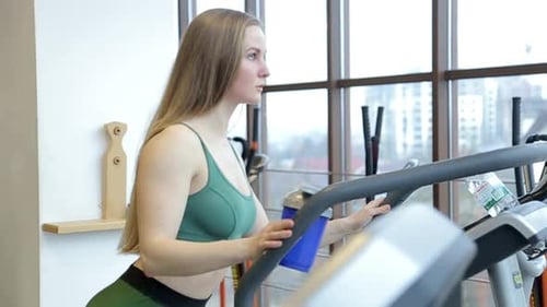 Woman Exercising on Treadmill in Gym