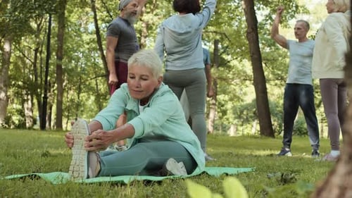 Aged Sportswoman Stretching in Park