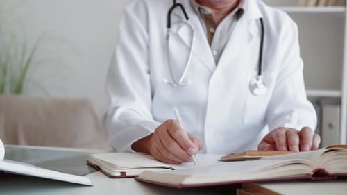 Doctor Studies and Takes Notes at Desk