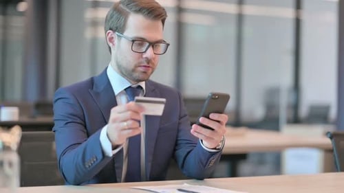 Businessman Reacting to Loss on Smartphone in Office