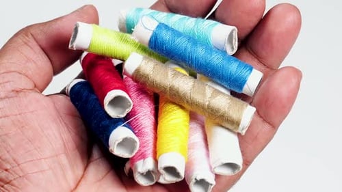 Hand Holding Colorful Sewing Thread Spools Macro Shot