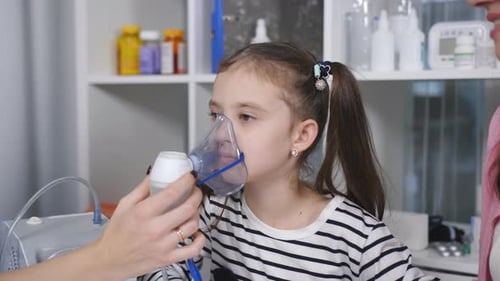 Retrato de una mujer pediatra y una niña con una máscara de inhalación de un nebulizador