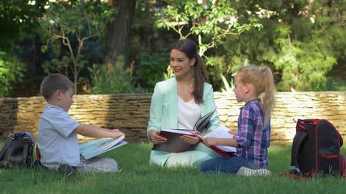 Teacher Reading with Children Outdoors in Park