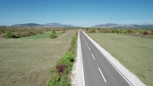 Aerial View Empty Asphalt Road on the Plateau Between Green Fields Highland Way